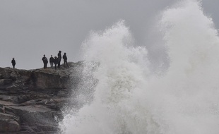 Les habitants de Batz-sur-Mer, dans l'Ouest de la France, regarde les immenses vagues venir se casser sur les rochers, la veille de l'arrivée de la tempête Carmen, le 1er janvier 2018.