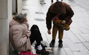 Une femme donne à un homme sans-abri.
