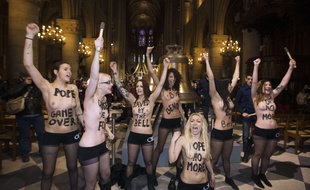 (FILES)-- This file photo taken on February 12, 2013 shows activists from the women's rights organisation Femen protesting in front of eight new bronze bells displayed in the nave of Notre-Dame de Paris Cathedral in Paris. Nine Femen members who participated in a demonstration at Notre-Dame de Paris in February 2013 are expected to appear in a Paris court on July 9, 2014 for "damage to a place of worship in a group". AFP PHOTO / JOEL SAGET