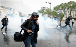 Les manifestants tentent d'échapper au nuage de gaz lacrymo lors des manifestations contre la loi Travail, à Paris le 12 mai 2016