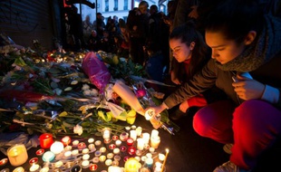 Des personnes déposent des bougies en hommage aux victimes des attentats rue de Charonne à Paris, le 14 novembre 2015