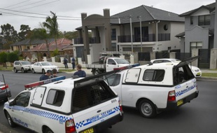 Des véhicules de police devant une maison où quatre personnes ont été arrêtées dans l'enquête antiterroriste sur le meurtre d'un comptable travaillant pour la police australienne, le 7 octobre 2015 à Sydney