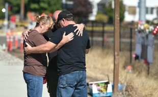 Des gens prient près de l'entrée de l'université d'Umpqua à Roseburg (Etats-Unis), dans l'Oregon, le 3 octobre 2015, quelques jours après le meurtre de dix personnes par un homme armé
