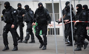 Des policiers de la brigade de recherche et d'intervention (BRI) marchent dans la rue le 09 mars 2009 à Paris, après leur intervention dans un immeuble au 51 de la rue Auguste Blanqui (XIII), où un homme armé s'était retranché dans son appartement aprés avoir blessé par balles un homme sur la voie publique à la hauteur du métro Corvisart.