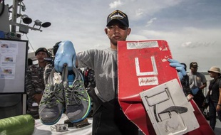 Un responsable indonésien montre le 5 janvier 2015 des débris de l'avion d'AirAsia qui s'est écrasé en mer, ainsi qu"une paire de chaussures récupérée sur les lieux