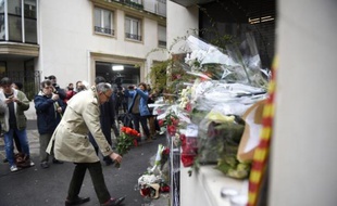 Un homme dépose des fleurs devant le siège de Charlie Hebdo à Paris le 8 janvier 2015