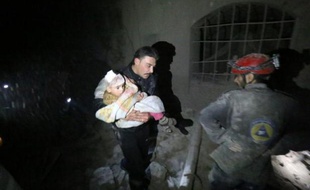Un homme porte secours à un enfant dans les décombres après un tir de roquettes à Alep, le 2 janvier 2014