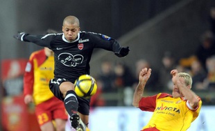 Le Valenciennois Mathieu Dossevi taclé par le Lensois, Yohan Demont, le 5 février 2011 à Lens.