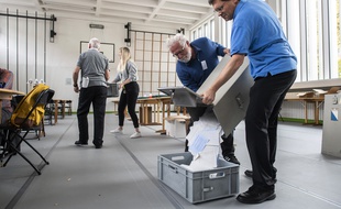 Des volontaires vident l'urne d'un bureau de vote de Zurich, en Suisse, le 20 octobre 2019.