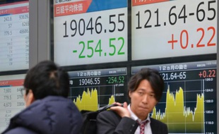Des piétons passent devant des tableaux indiquant les cours de la Bourse, à Tokyo le 10 décembre 2015