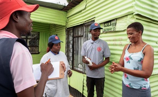 Les membres de la Croix-Rouge internationale fournissent des conseils de prévention pour contenir l'épidémie de coronavirus COVID-19, dans le quartier informel de Protea à Soweto, le 23 mars 2020.