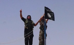 Photo d'archive extraite du compte twitter jihadiste Al-Baraka news le 11 juin 2014 montrant des militants de l'EI et leur drapeau noir sur un fort situé entre la province irakienne de Ninive et la ville syrienne de Al-Hasakah