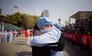 A droite, un soignant de Wuhan serre dans ses bras un compatriote de la province de Jiangsu venu les aider pendant la crise, le 19 mars 2020.