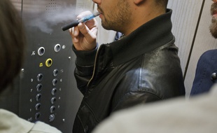 Paris el 06 octobre 2013. Illustration personne en train de vapoter dans un ascenseur, lieu ferme confine. Vapoteur, vapotage, cigarette electronique.