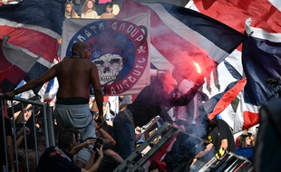 Un supporter parisien tient dans sa main un fumigène