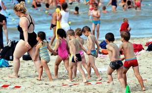 Des enfants d'un camp de vacances et leur monitrice sur la plage le 25 juillet 2013 à Bray-Dunes dans le nord de la France