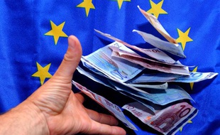 Une personne place des billets en euro devant un drapeau européen.