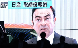 Un homme passe devant un écran qui retransmet les informations sur l'arrestation de Carlos Ghosn à Tokyo.
