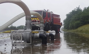 Des pompiers pompent l'eau qui inonde l'autoroute A13 entre Orgeval et Villennes-sur-Seine dans les Yvelines, le 12 juin 2018.