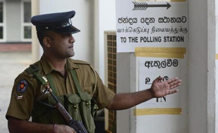 Un policier sri-lankais montre la voie vers le bureau de vote à Colombo le 8 janvier 2015 jour de l'éléction présidentielle