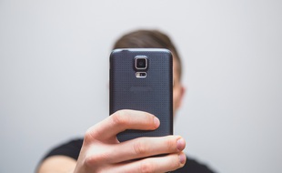 Un homme faisant un selfie avec son téléphone portable.