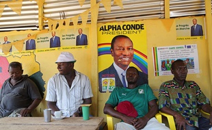 Des Guinéens attablés dans un restaurant de la capitale Conakry sous des affiches du président sortant Alpha Condé, le 17 octobre 2015.