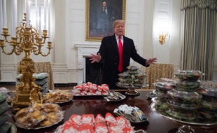 Dans la salle à manger de la Maison Blanche, le président Donald Trump s'exprime lors d'une cérémonie en l'honneur des joueurs de l'équipe de football des Clemson Tigers. Des plats de Fast-food payés par le chef d'Etat américain sont entreposés.