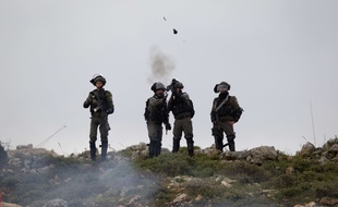 Des soldats israéliens lancent des grenades lacrymogènes à al frontière entre Gaza et Israël, vendredi 30 mars.