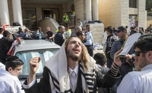 Un juif ultra-orthodoxe prie devant l'entrée de la synagogue à Jérusalem le 18 novembre 2014, quelques heures après une attaque qui a fait quatre morts parmi les fidèles