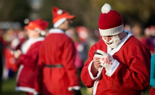Un homme déguisé en père Noël utilise un smartphone.