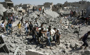 Des personnes transportent un corps après des frappes de l'armée de l'air du régime syrien, le 21 septembre 2015 à Alep