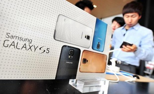 Un homme regarde un téléphone portable de modèle Galaxy S5 de Samsung dans un magasin de Séoul, le 27 mars 2014