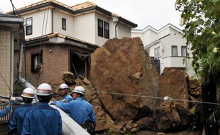 Une maison et un poteau électrique endommagés par une chute de pierres lors du passage du typhon Wipha, le 16 octobre 2013 à Kamakura, dans la banlieue de Tokyo