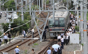 Les passagers d'un train ont dû rejoindre la gare à pied après le tremblement de terre à Osaka, le 18 juin 2018.