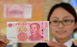 Une employée de banque montre le nouveau billet de 100 yuans, à Handan, dans la province du Hebei, le 12 novembre 2015.