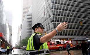 Un policier fait des gestes près des camions de pompiers après qu'un hélicoptère s'est écrasé au sommet d'un immeuble dans le centre-ville de Manhattan, à New York, le 10 juin 2019.