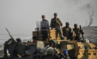 La ville syrienne de Kobané, au loin, alors que l'armée turque prend position, dans la ville de Suruc, à la frontière avec la Syrie, le 3 octobre 2014
