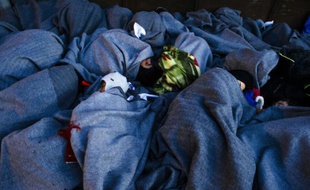 Des migrants endormis sous des couvertures sur le rivage de l'île de Lesbos le 15 octobre 2015 en provenance de Turquie