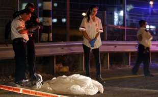 Des membres des forces de la sécurité israélienne et des secouristes devant le corps d'un palestinien abattu alors qu'il tentait de poignardé un israélien dans une station-service de Cisjordanie occupée, sur l'autoroute 443 au sud-ouest de Ramallah, le 9 août 2015
