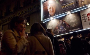 Des gens font la queue devant une salle de cinéma parisienne.