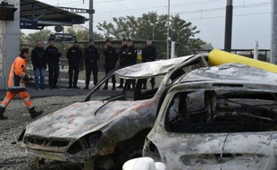 Gendarmes le 21 octobre 2015 devant des véhicules calcinés à la gare de Moirans, lors de violences commises la veille par des gens du voyage