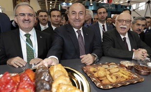 Mevlut Cavusoglu (au centre) propose des pâtisseries aux journalistes, mercredi 8 mars, à Berlin.