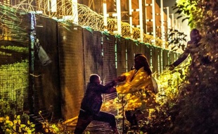 Des migrants tentent de s'entroduire dans les quais d'Eurotunnel, protégés par des barrières metalliques, le 30 juillet 2015 pa Coquelles