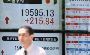 Un opérateur boursier passe devant un tableau de cotation des indices du Nikkei, le 11 mai 2015 à Tokyo