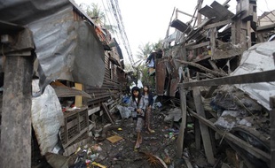 Une femme marche dans les décombres de maisons touchées par une explosion, le 29 décembre 2011, à Rangoun (Birmanie).