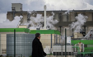 Un passant regarde la fumée s'élever d'un bâtiment de la société SAIPOL (groupe Avril) classé SEVESO, touché par un incendie, à Grand-Couronne, près de Rouen, dans le nord de la France, le 13 mars 2020.
