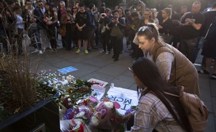 Deux jeunes femmes déposent des fleurs au Albert Square de Manchester en hommage aux victimes de l'attentat-suicide.