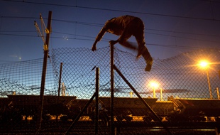 Un migrant franchit une barrière pour accéder au site d'Eurotunnel, à Calais, en août 2015.