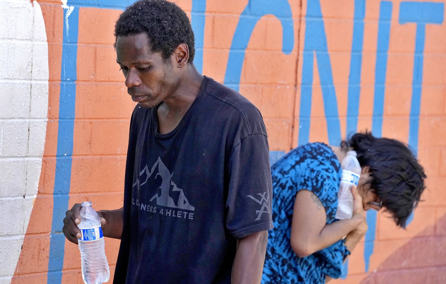 Des sans-abris essaient de se rafraîchir avec de l'eau fraîche devant le Justa Center, un centre de jour pour les sans-abris de 55 ans et plus, vendredi 14 juillet 2023 dans le centre de Phoenix.