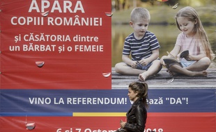 Une jeune femme passe devant une affiche indiquant: